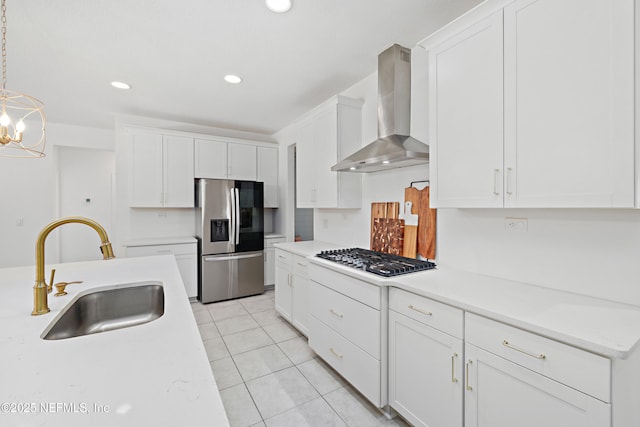 kitchen featuring a sink, white cabinetry, stainless steel appliances, wall chimney exhaust hood, and light countertops