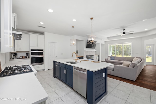 kitchen featuring blue cabinets, visible vents, a sink, open floor plan, and stainless steel appliances