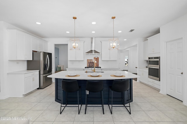 kitchen with a center island with sink, visible vents, stainless steel appliances, a kitchen bar, and wall chimney exhaust hood