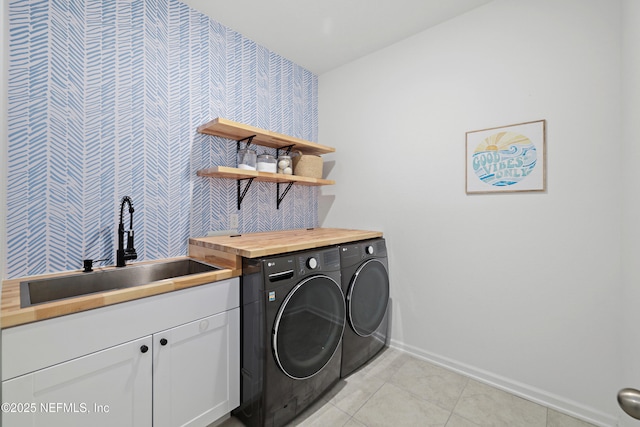 clothes washing area featuring baseboards, light tile patterned flooring, cabinet space, independent washer and dryer, and a sink