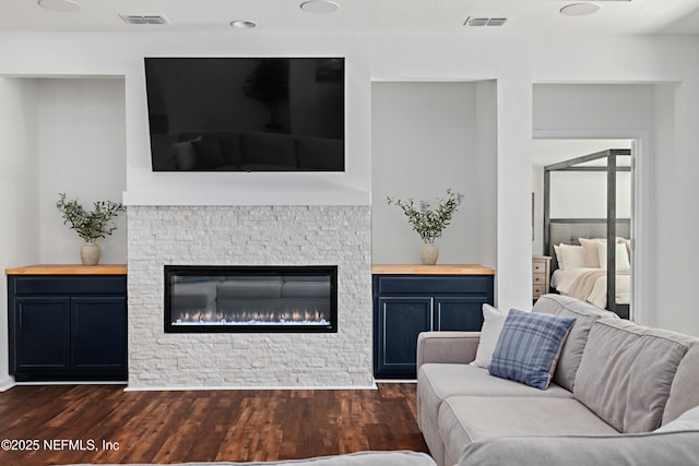 living room featuring visible vents, a fireplace, and dark wood-style flooring