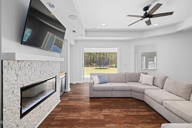 unfurnished living room featuring visible vents, dark wood-style floors, recessed lighting, a fireplace, and a raised ceiling