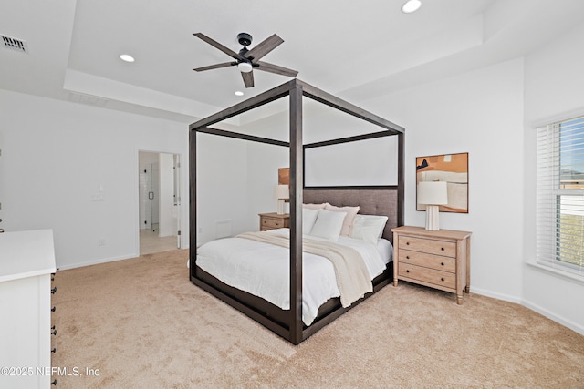 bedroom with baseboards, a raised ceiling, and light colored carpet