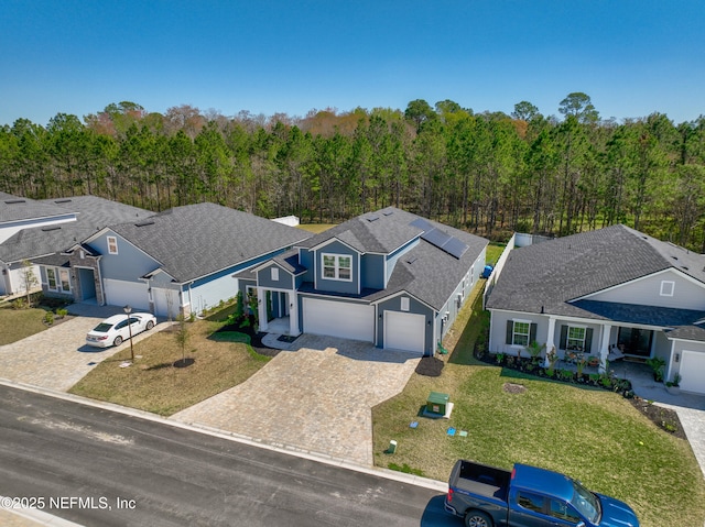 view of front of home featuring a front lawn, decorative driveway, fence, and a view of trees