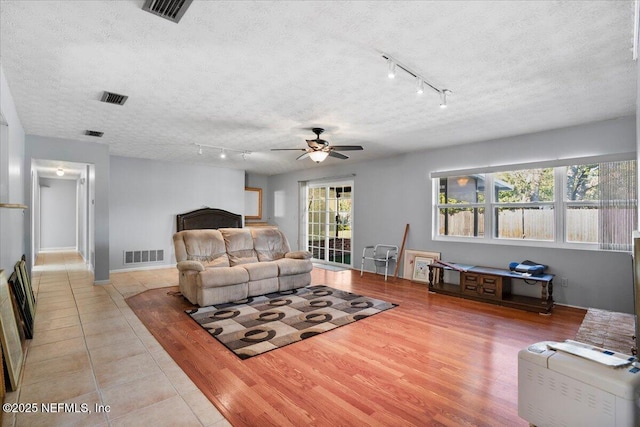 tiled living room with ceiling fan, a textured ceiling, and track lighting