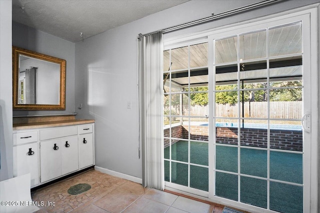 doorway to outside with a wealth of natural light, a textured ceiling, and light tile patterned flooring