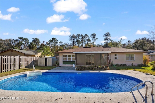 view of swimming pool featuring a patio area and a storage shed