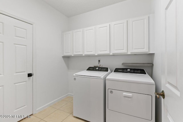 laundry area featuring separate washer and dryer, cabinets, a textured ceiling, and light tile patterned flooring