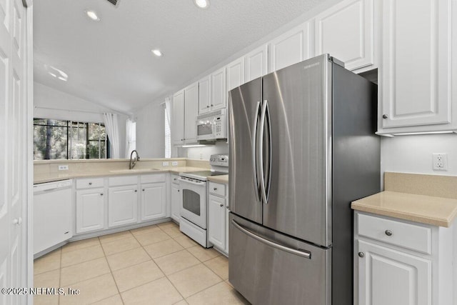 kitchen with lofted ceiling, sink, white appliances, white cabinets, and light tile patterned flooring