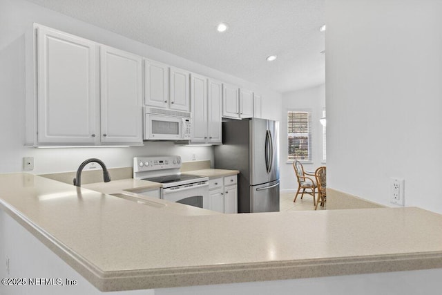 kitchen with white cabinetry, sink, white appliances, and kitchen peninsula