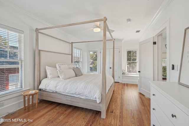 bedroom featuring multiple windows, ornamental molding, and light hardwood / wood-style floors