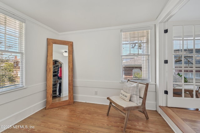 living area featuring hardwood / wood-style flooring, a wealth of natural light, and ornamental molding