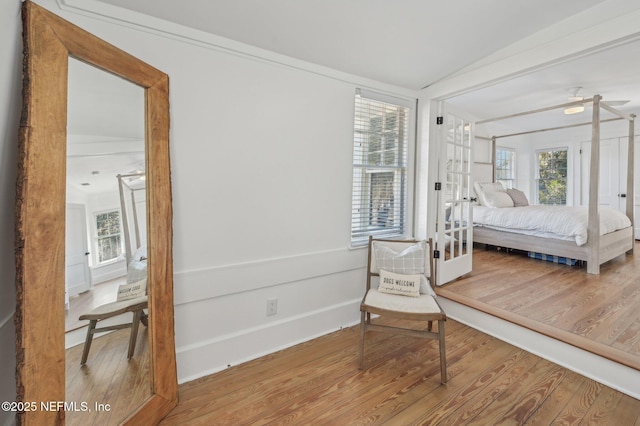 bedroom with french doors, lofted ceiling, and wood-type flooring