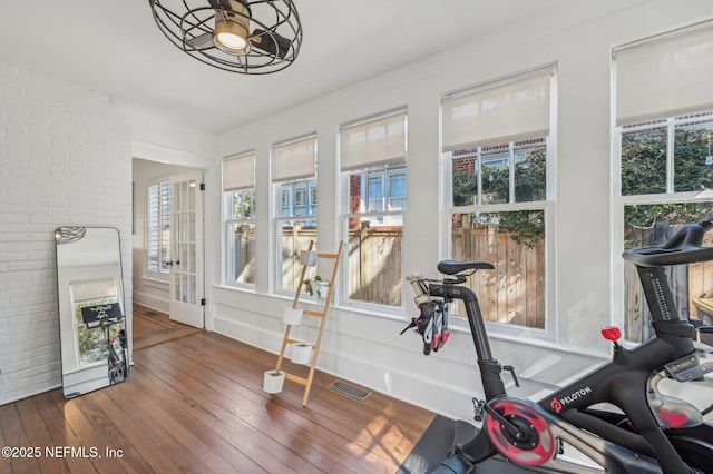 exercise room featuring brick wall and dark hardwood / wood-style floors