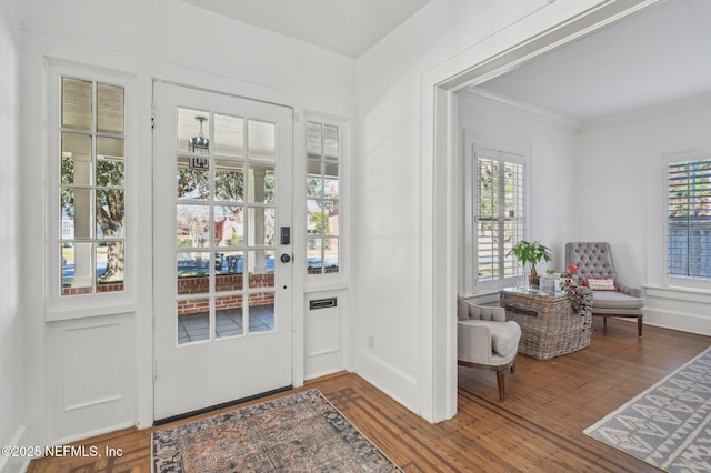 doorway to outside with ornamental molding and dark hardwood / wood-style floors