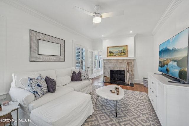 living room featuring a fireplace, dark wood-type flooring, ornamental molding, and ceiling fan