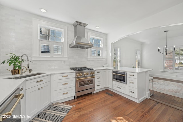 kitchen with extractor fan, sink, white cabinets, kitchen peninsula, and stainless steel appliances