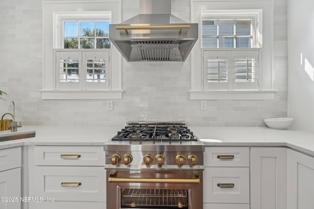 kitchen featuring tasteful backsplash, stainless steel stove, extractor fan, and white cabinets