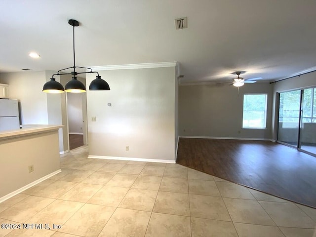 tiled spare room with ornamental molding and ceiling fan