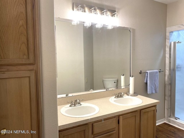 bathroom featuring vanity, a shower with door, and toilet