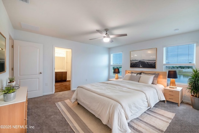 carpeted bedroom with multiple windows, ceiling fan, and ensuite bath