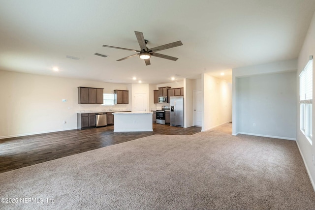 unfurnished living room with ceiling fan and dark carpet