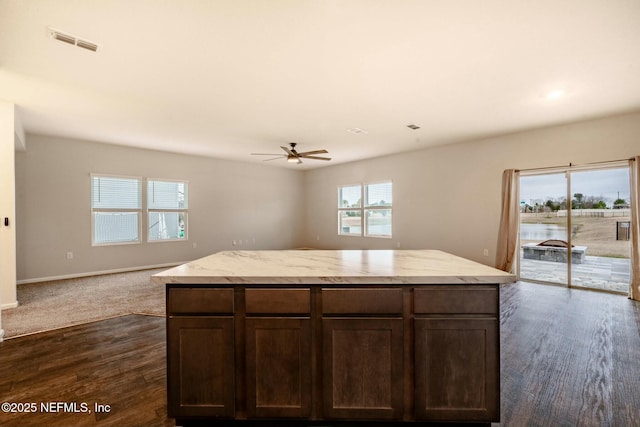 kitchen featuring ceiling fan, plenty of natural light, a center island, and dark brown cabinets