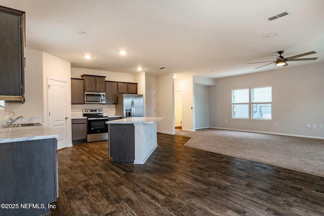 kitchen with sink, dark hardwood / wood-style flooring, a center island, dark brown cabinetry, and stainless steel appliances