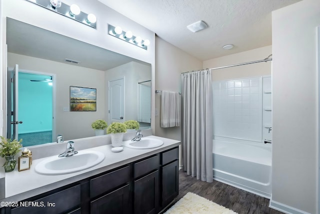 bathroom featuring wood-type flooring, shower / bath combination with curtain, a textured ceiling, and vanity