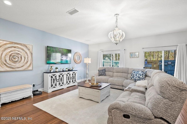 living room with a healthy amount of sunlight, hardwood / wood-style floors, a notable chandelier, and a textured ceiling