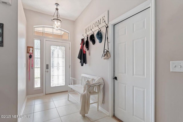 mudroom featuring light tile patterned flooring, an inviting chandelier, and a healthy amount of sunlight