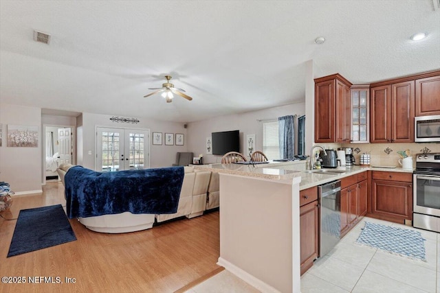 kitchen featuring kitchen peninsula, french doors, sink, appliances with stainless steel finishes, and a textured ceiling