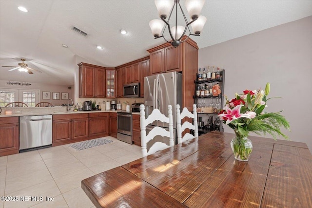 kitchen featuring light tile patterned floors, sink, stainless steel appliances, ceiling fan with notable chandelier, and lofted ceiling