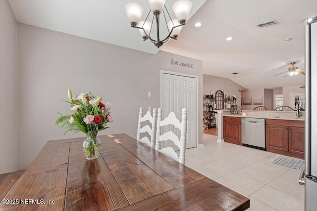 dining area with sink, ceiling fan with notable chandelier, light tile patterned floors, and lofted ceiling