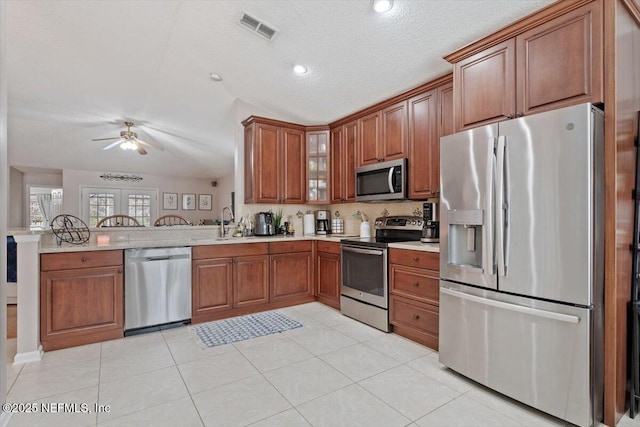 kitchen with a textured ceiling, stainless steel appliances, sink, kitchen peninsula, and light tile patterned floors