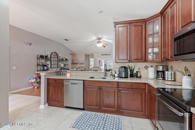 kitchen with appliances with stainless steel finishes, light tile patterned floors, sink, kitchen peninsula, and ceiling fan