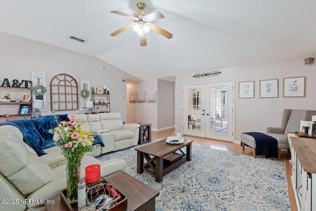 living room featuring ceiling fan, french doors, light wood-type flooring, a textured ceiling, and lofted ceiling