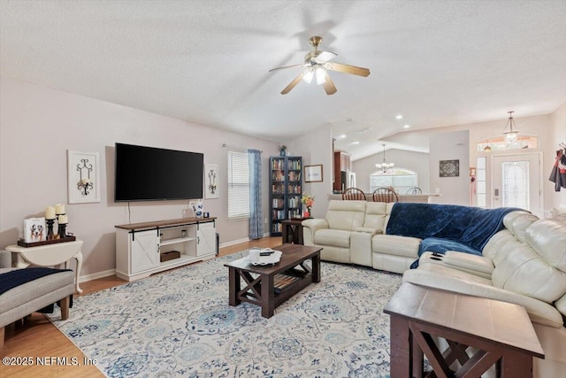 living room with a healthy amount of sunlight, a textured ceiling, light wood-type flooring, and vaulted ceiling