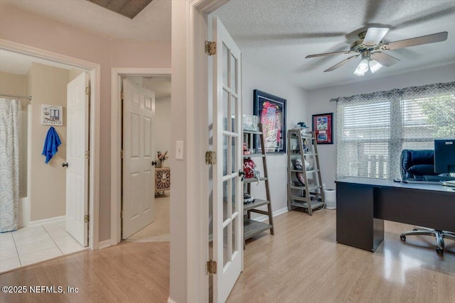 home office with ceiling fan, light hardwood / wood-style floors, and a textured ceiling