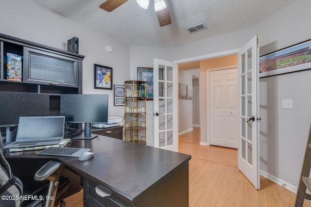 home office with light wood-type flooring, a textured ceiling, and french doors