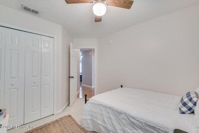 carpeted bedroom with ceiling fan, a textured ceiling, and a closet