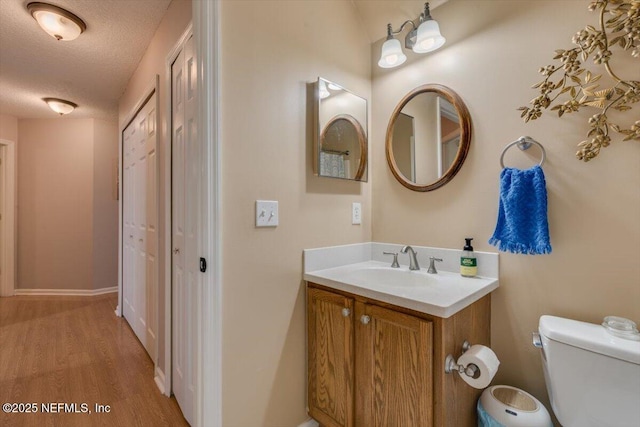 bathroom with wood-type flooring, toilet, a textured ceiling, and vanity