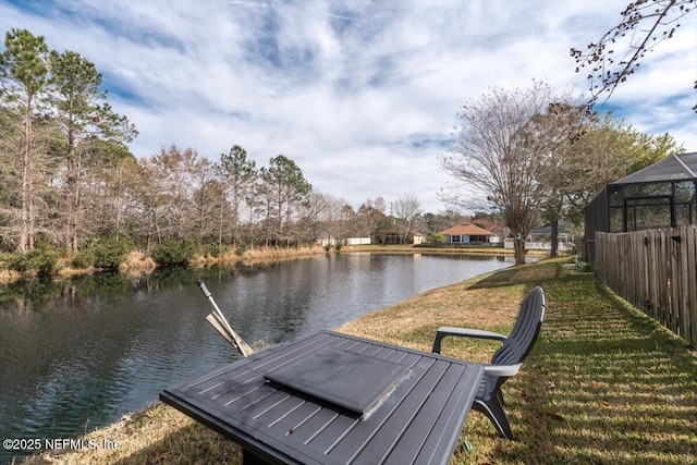 view of dock with glass enclosure, a water view, and a yard