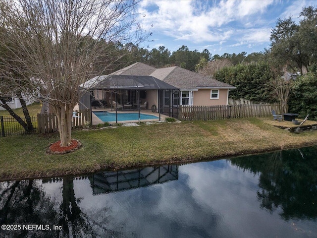 back of property with a fenced in pool, a lanai, a yard, and a water view