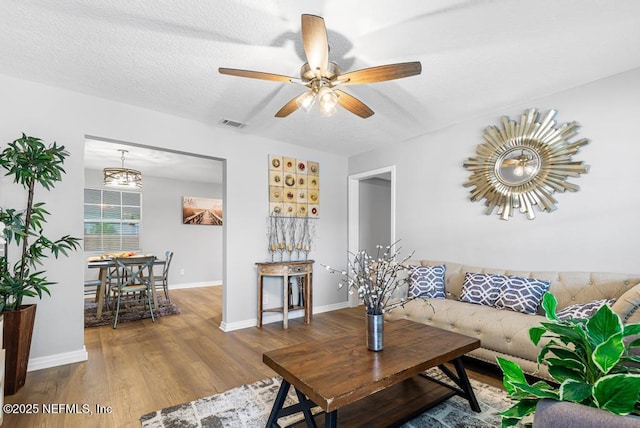 living room featuring hardwood / wood-style flooring, ceiling fan, and a textured ceiling