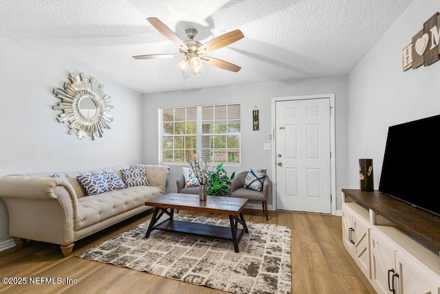 living room with light wood-type flooring, a textured ceiling, and ceiling fan