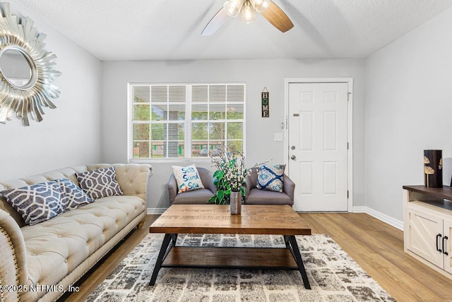 living room with a textured ceiling, light hardwood / wood-style flooring, and ceiling fan