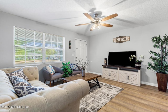 living room with ceiling fan, light hardwood / wood-style floors, and a textured ceiling