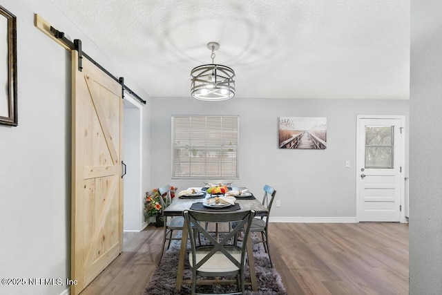 dining space with hardwood / wood-style floors, a textured ceiling, a barn door, and a healthy amount of sunlight