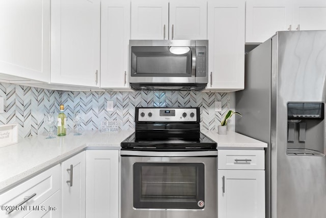 kitchen with white cabinets, stainless steel appliances, light stone countertops, and tasteful backsplash